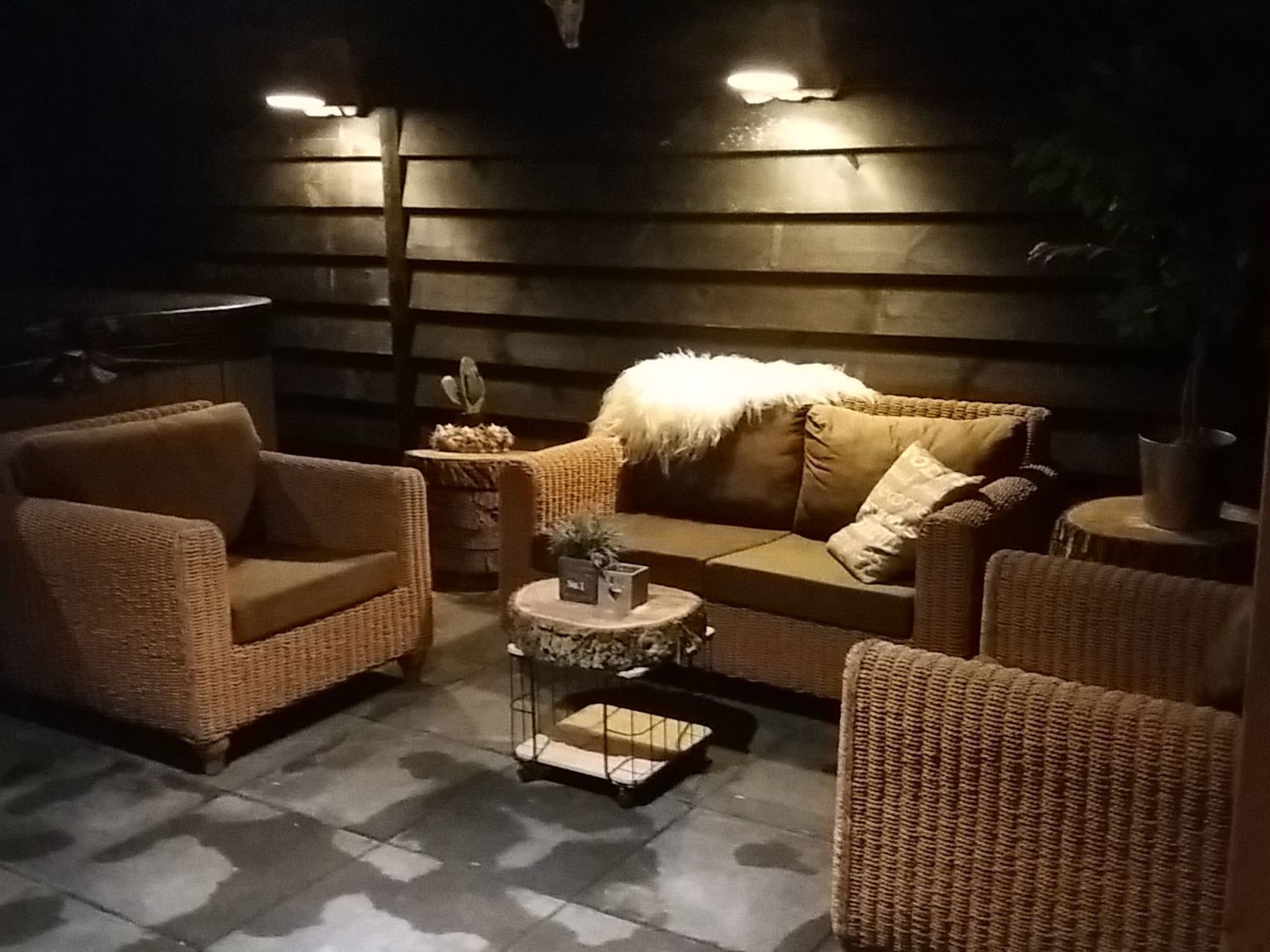 A cozy lounge area with wicker furniture, a round coffee table, and a cactus plant.