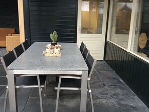 Ett rektangulärt bord med metallben och en grå bordsskiva, omgivet av svarta stolar. En liten kaktus och några dekorativa föremål står på bordet.