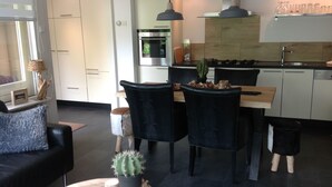 Une cuisine moderne avec un coin repas, comprenant une table en bois, des chaises noires et un cactus en guise de décoration centrale.