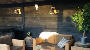 Un espace extérieur accueillant, aménagé avec des meubles en osier, une petite table et des objets décoratifs.