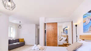Een moderne slaapkamer met een groot bed, een bank, een houten kledingkast en een schilderij aan de muur.