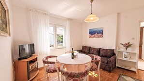 A living room with a round table, patterned chairs, a sofa, a television, and a painting on the wall. - Apartment Dragica by Interhome (Polje)