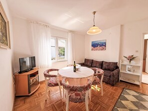 A living room with a round table, patterned chairs, a sofa, a television, a painting, and a bookshelf. - Apartment Dragica by Interhome (Polje)