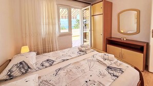 A bedroom with a bed, a bedside table, a mirror, and a view of the outdoors. - Apartment Dragica by Interhome (Polje)