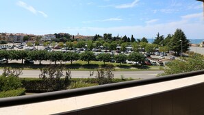 Une vue depuis une fenêtre donnant sur un parking, avec des arbres et des bâtiments en arrière-plan.
