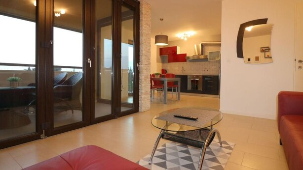 Un salon moderne avec un canapé rouge, une table en verre et un coin repas avec des chaises rouges.