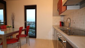 Une cuisine moderne avec un coin repas, une vue à travers une porte vitrée et un balcon.