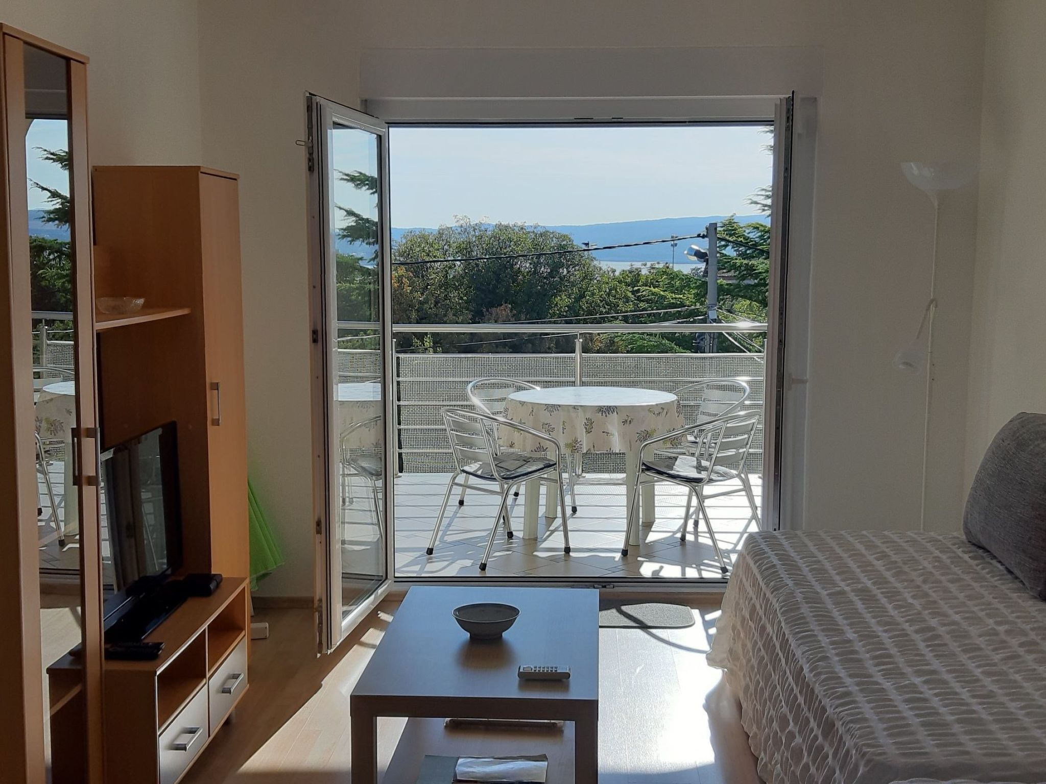 Una habitación con balcón, televisión, mesa y cama.