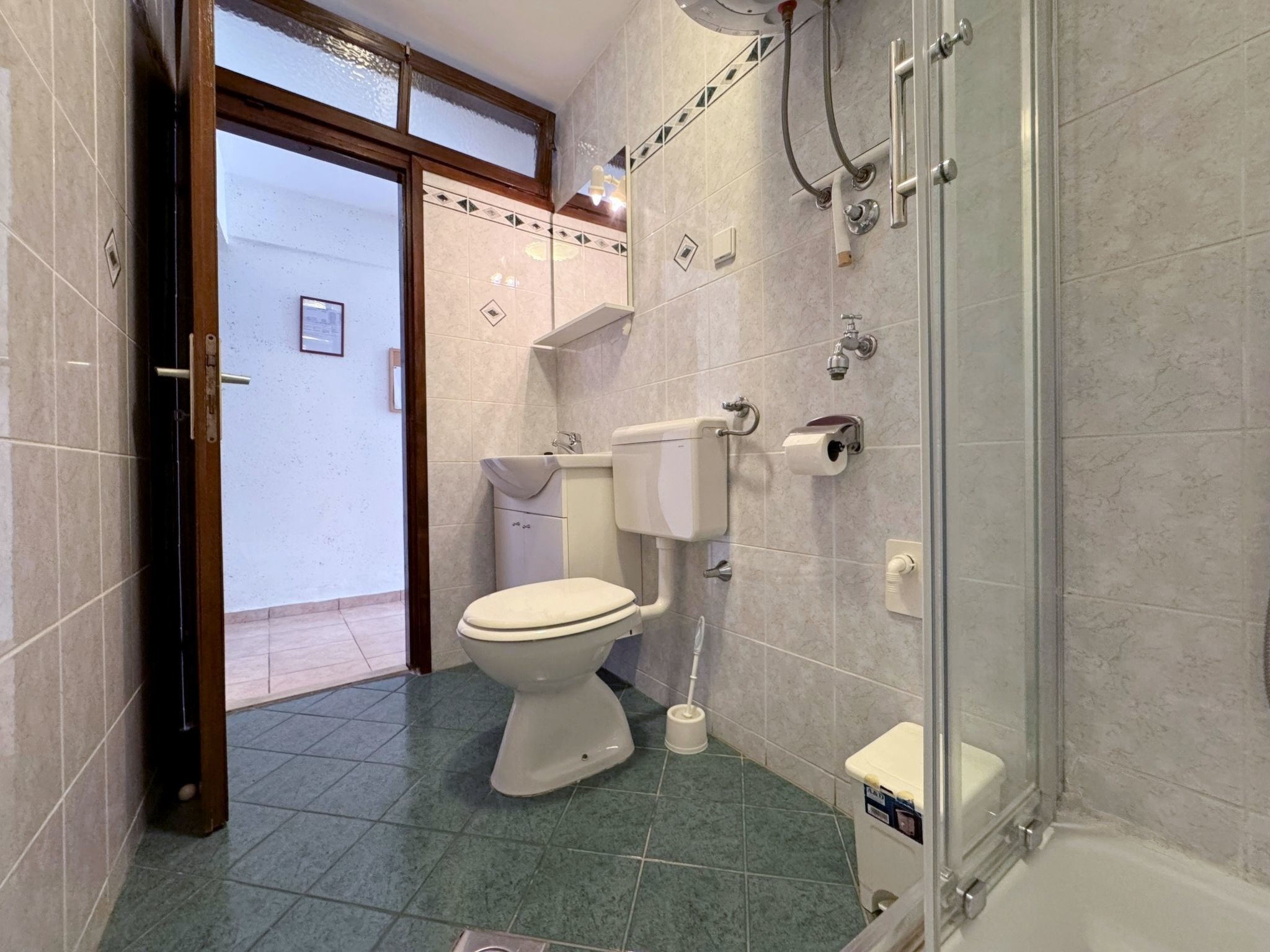 A bathroom with a toilet, sink, and shower.