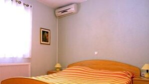 Un dormitorio con una cama individual, una mesita de noche, una lámpara y un aire acondicionado instalado en la pared.