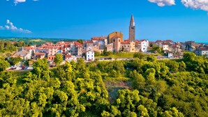 Un pueblo histórico con una iglesia y torre destacadas, rodeado de vegetación exuberante y edificios con tejados rojos.