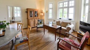Een ruime woonkamer met een houten eettafel, stoelen, een bank en een televisie.