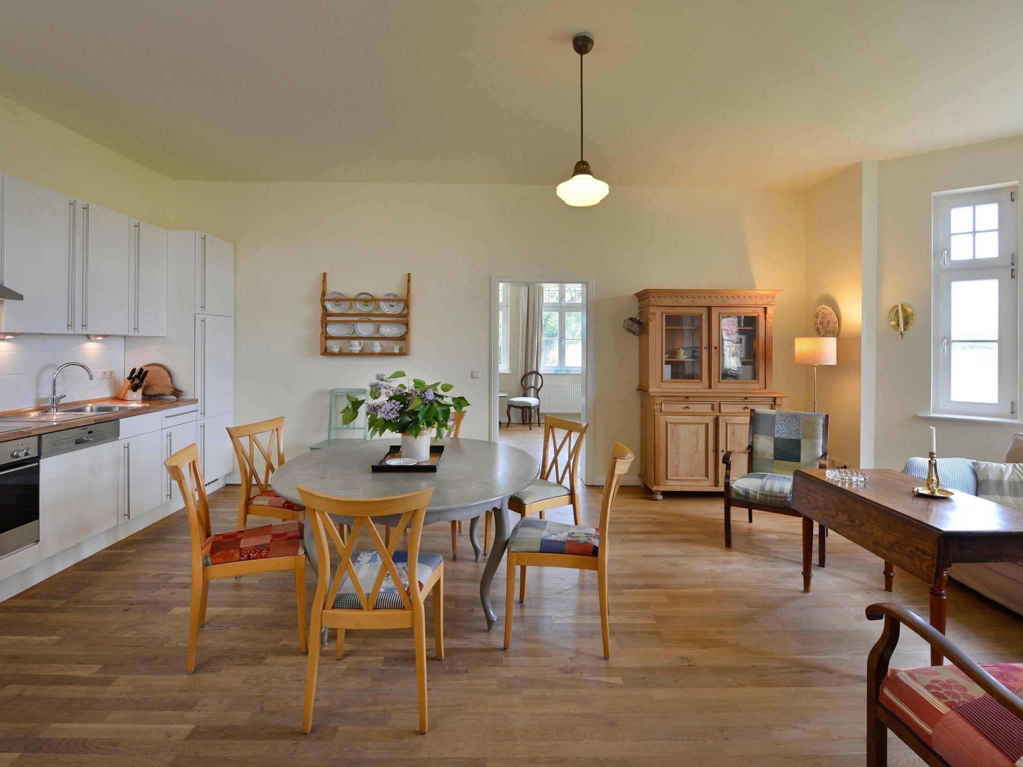 A spacious kitchen with white cabinets, a dining table with chairs, and a wooden bench.