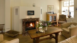 Een gezellige woonkamer met een open haard, een houten salontafel en comfortabele zitplaatsen.