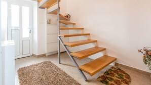 Un interno moderno con una scala a chiocciola, mobili bianchi e una piccola pianta.