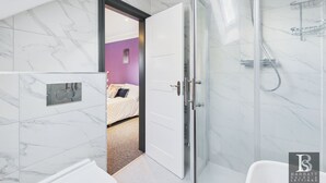 Een moderne badkamer met een glazen douchecabine, een wit toilet en een marmeren vloer.