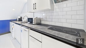 Een moderne keuken met witte kastjes, een magnetron, een ingebouwde oven en een wasmachine.