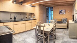Eine moderne Küche mit Holzschränken, einem Esstisch, Stühlen und einem eingebauten Herd.
