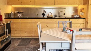 Eine moderne Küche mit Holzausstattung, einem Edelstahlspülbecken und einem Essbereich mit Tisch und Stühlen.