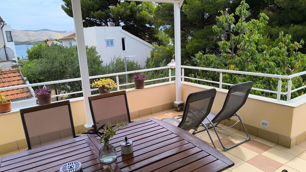 A covered outdoor seating area with a table and chairs, potted plants, and a view of the sea and hills. - für 3 Personen  + 1 Kind ca. 68 m² in Žaboric, Dalmatien (Gespanschaft Sib by Interhome (Brodarica/Žaborić)