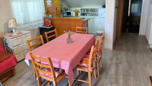 A cozy dining area with a red and white checkered tablecloth, wooden chairs, and a small vase with flowers. A kitchen is visible in the background with white cabinets and a microwave. - für 3 Personen  + 1 Kind ca. 68 m² in Žaboric, Dalmatien (Gespanschaft Sib by Interhome (Brodarica/Žaborić)