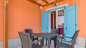 An outdoor patio with a table and four chairs, a blue door, and a tiled floor. - für 2 Personen ca. 40 m² in Veli Lošinj, Adriaküste Kroatien (Kroatische I by Interhome (Lošinj / Veli Lošinj)