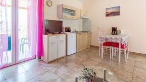 A compact kitchen with a microwave, a small refrigerator, and a TV on a cabinet. There's a dining table with chairs and a small potted plant. - für 2 Personen ca. 40 m² in Veli Lošinj, Adriaküste Kroatien (Kroatische I by Interhome (Lošinj / Veli Lošinj)