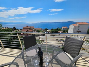 A terrace with a table and chairs overlooking a coastal view. - Wohnung für 6 Personen mit Meerblick by Interhome (Novi Vinodolski)