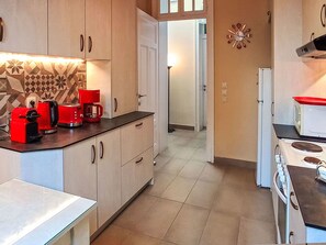 A kitchen with light-colored cabinets, a red coffee maker, a white stove, and a patterned backsplash. - Wohnung mit Meerblick und großer Terrasse by Interhome (Faliraki)