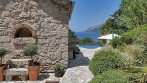 A stone building with a pool, surrounded by greenery and a view of the sea. - Villa Relax Brela by Interhome (Brela)