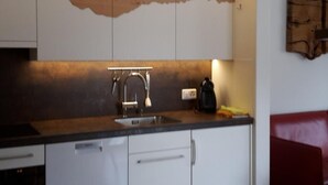 Eine Küche mit weißen Schränken, einer Holz-Spritzschutzwand und einem Edelstahl-Spülbecken.