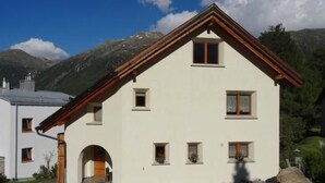 Ein zweistöckiges Gebäude mit weißer Fassade, zahlreichen Fenstern und einem Holzdach.