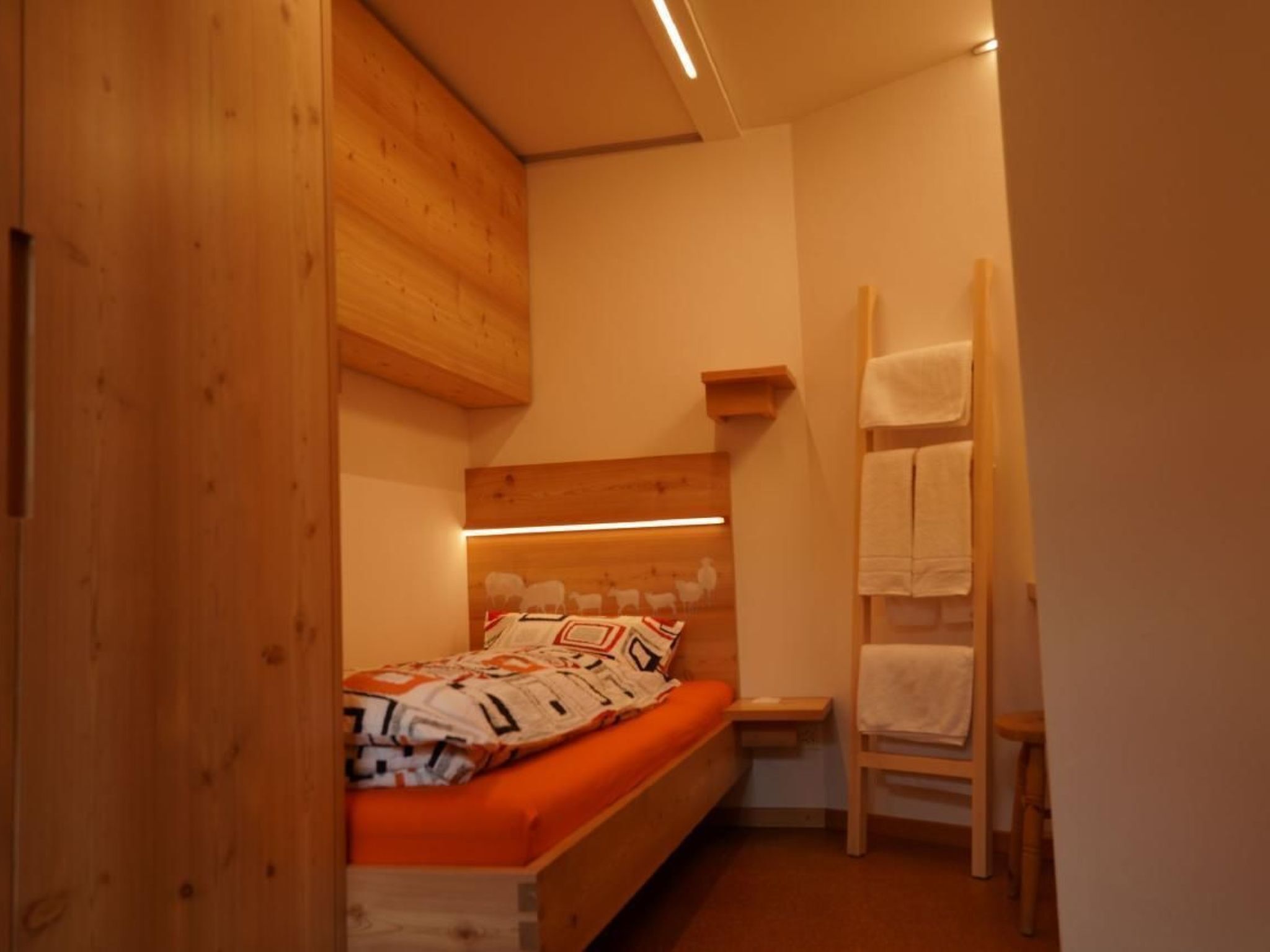 Una camera da letto piccola e accogliente con un letto a castello in legno, un comodino e una mensola a muro.