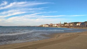 En strand med klart himmel og bygninger i baggrunden.