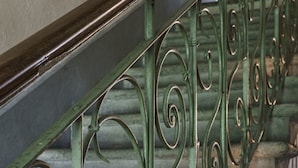 Un escalier avec des rampes en métal vert ouvragé et des marches en bois.