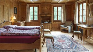 Une chambre dans une cabane en bois, avec un lit, deux chaises, un bureau et une grande fenêtre.