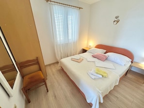 A bedroom with a bed, a chair, a nightstand, and a window with curtains. - für drei Personen by Interhome (Klek)