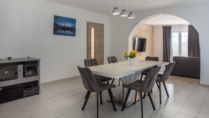 A modern dining area with a large table, chairs, and a kitchen unit with appliances. - Ferienvilla , Schwimmbad, Imotski, Makarska by Interhome (Donji Vinjani)