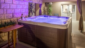 A hot tub with a wooden table and chairs, surrounded by plants and a stone wall. - Ferienvilla , Schwimmbad, Imotski, Makarska by Interhome (Donji Vinjani)