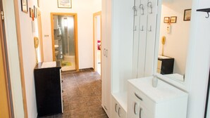 Un couloir d’hôtel avec une salle de bain, une coiffeuse avec un miroir et une armoire.