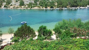 Une vue sur la côte, avec une eau turquoise et limpide, une plage de sable et un quai pour bateaux.