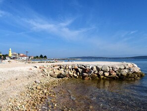 Eine felsige Küstenlinie mit einer Steinmauer, klarem Wasser und einer entfernten Ansicht einer Stadt.