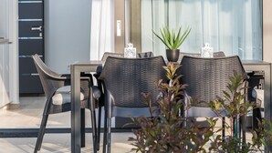 A modern outdoor dining area with wicker chairs and a table, a potted plant, and a glass door leading to a building. - Villa Rossa by Interhome (Ugljan/Kukljica)