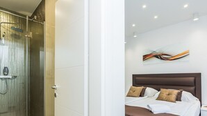 A modern hotel room with a glass shower enclosure, a neatly made bed with brown bedding, and a wall-mounted abstract art piece. - Villa Rossa by Interhome (Ugljan/Kukljica)