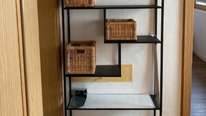 Une étagère en métal noir, dotée de paniers en osier et ornée d’un tableau encadré, le tout placé devant un mur à texture.