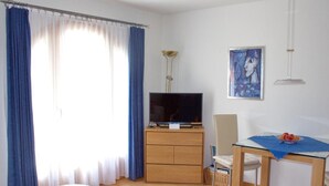 Una stanza moderna con un armadio in legno, una televisione, un tavolo da pranzo con sedie e un quadro appeso al muro.