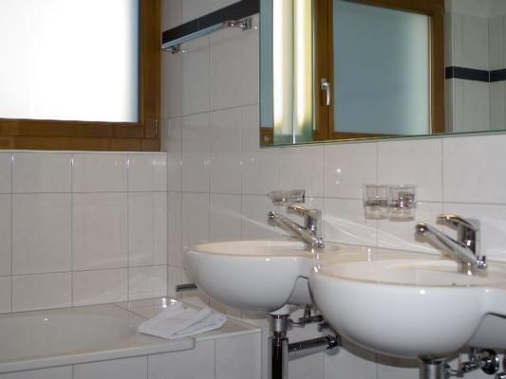 A bathroom with two sinks, a mirror, and a towel rack.