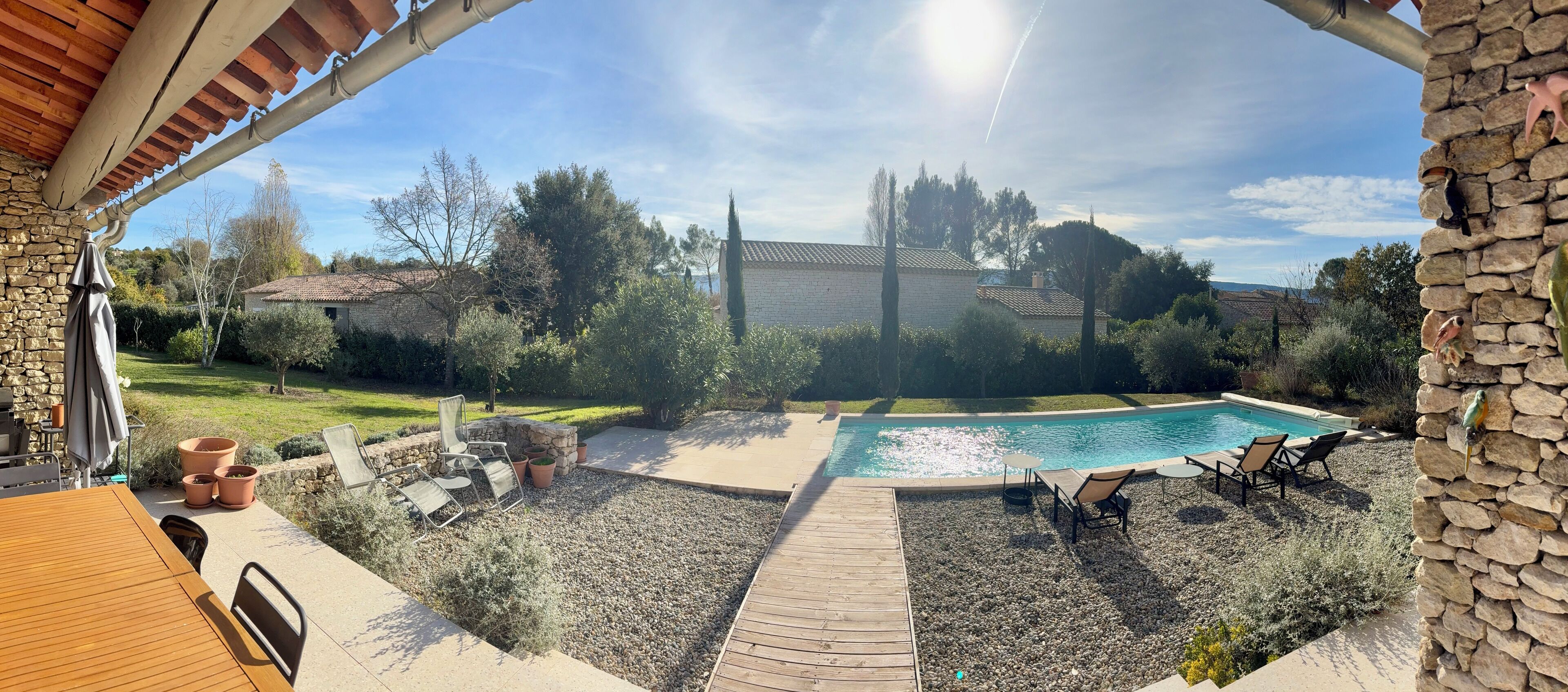 Un pati amb piscina, mobiliari de pati i una paret de pedra.