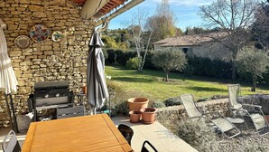 A patio area with a stone wall, a grill, outdoor furniture, and a view of the garden. - Mas de charme "LUMEA" with swimming pool near Gordes - Luberon (Gordes)
