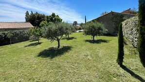 A stone building with a tiled roof, surrounded by a well-maintained lawn and several trees. - Mas de charme "LUMEA" with swimming pool near Gordes - Luberon (Gordes)